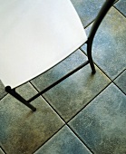 Moderner Stuhl auf graumeliertem Fliesenboden