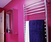 Handtuchtrockner aus Edelstahl mit blauem Handtuch vor pinkfarbener Wand