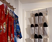 Garderobe mit Kimonos und Schuhe in Stofftaschen an Tür gehängt