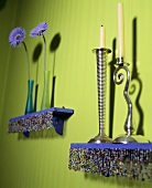 Kerzenleuchter aus Metall und Vasen mit Blume auf Regal mit Perlenbordüre