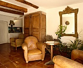 Alte Ledersessel auf Fliesenboden in französischem Landhaus-Wohnzimmer