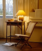 Brennende Lampe auf Bambus-Tisch mit gepolstertem Bambusstuhl vor weißem Klavier