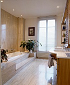 Modernes Marmor-Bad mit Stufen zu eingebauter Wanne und Doppel-Waschtisch aus Holz