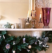 Leuchter aus Zinn, violette Glasvase und Weihnachtsdeko in Silber auf weißem Kaminsims