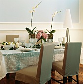 Zarte Farben auf festlich gedecktem Tisch mit Orchideen, Hortensien und bestickter Voile-Decke
