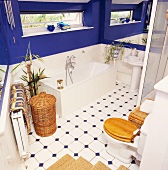 Knallblau gestrichene Wände in weißem Landhaus-Badezimmer mit Weidenkörben und Toilettensitz aus Holz