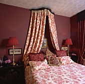 Doppelbett mit rot-weisser Bettwäsche und Bettvorhang in einem roten Schlafzimmer
