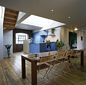 Langer Esstisch mit Stühlen und eine blaue Küche in einer Loftwohnung