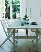 Weisser Holztisch mit Geschirr und passende Stühle auf Holzboden weißem Holzboden