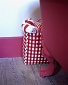 Rot-weiss karierte Tasche mit rot-weissen Handtüchern neben einer frei stehenden roten Badewanne