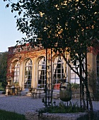 Italienische Villa mit Rudnbogenfenstern, im Vordergrund ein alter Blecheimer