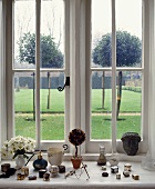 Sammlung von kleinen Porzellandosen auf einer Fensterbank mit Blick auf den Garten