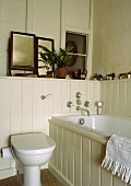 Ein teilweise vertäfeltes Badezimmer mit Badewanne und Toilette