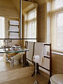Glas und Edelstahl Becken an der Spiegelwand im modernen Bad mit weißen Handtüchern auf dem hölzernen Handtuchhalter