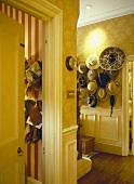 Gemusterte Tapeten im gelben Saal mit einer Sammlung von Hüten auf Wand-Kleiderständer