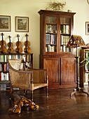 Antikes Bücherregal und kolonialer Rohrstuhl im Musikzimmer mit Holzfußboden und einer Sammlung von Geigen