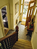 Blick von der Treppe auf den schwarz-weiß-karierten Hausflur vor offener Haustüre