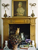 Ein Portrait hängt über dem Kamin, vor dem ein getrocknetes Blumen-Arrangement steht