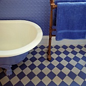 Ein Detail aus einem blau-weißen Badezimmers mit einer freistehenden Badewanne und einen Handtuchhalter aus Holz