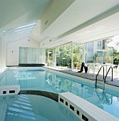 Moderner, langgestreckter Swimmingpool in Weiß mit schwarzen Elementen und offener Glasfront zum Innenhof