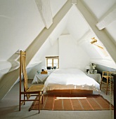 Modernes Doppelschlafzimmer mit ausgefallen Holzstühlen in weiss gestrichenem Spitzboden in Fachwerkhaus