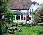 Gartenansicht eines traditionellen, mit weißem Holz verschalten Landhauses mit Wintergarten und Terrasse