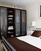 Schlafzimmer mit mattierten Glastüren und integrierter Beleuchtung in modernem Schlafzimmer in Grau- und Brauntönen
