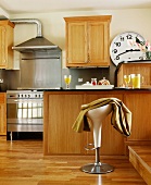 Moderne Küche aus Holz mit Edelstahl-Kocheinheit und Hocker vor Frühstückbar