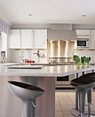 Moderne Küche mit Edelstahlkocheinheit, weissen Fronten, Granit-Arbeitsplatte und integrierter Frühstücksbar