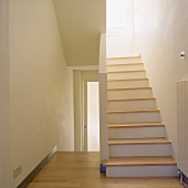 Moderne weiße Treppe mit Holzstufen in einem Treppenhaus mit Holzfußboden