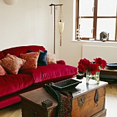Rotes Polstersofa und eine antike Holztruhe in einem Wohnzimmer