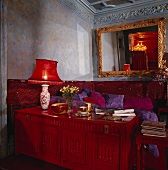 Rote Lampe auf einer rot geschnitzten Truhe im Wohnzimmer
