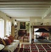 Ein ländliches Wohnzimmer mit einem Sofa und einem offenen Kamin als Trennwand in der Mitte