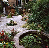 Ein gapflasterter Stadtgarten mit einem kleinen runden Teich
