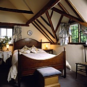 Schlafzimmer mit kleinen Fenstern, Balkendecke und antikem Mahagonibett