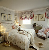 Schlafzimmer mit Spitzenbettdecke und Sessel und Jalousien mit floralem Muster