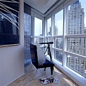 Schwarzer Ledersessel und Teleskop am Fenster mit Blick auf Wolkenkratzer