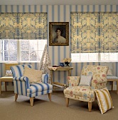 Blau-weiss gemusterte Vorhänge und blau-weiss gestreifte Tapete in einem Wohnzimmer mit Sesseln