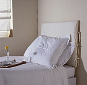 Frühstückstablett auf einem Einzelbett mit weisser Bettwäsche