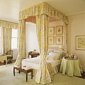 Himmelbett mit grün-gelb gemusterten Vorhängen in einem Schlafzimmer mit cremefarbenem Teppich