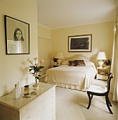 Ein cremefarbenes Schlafzimmer mit Doppelbett, Kommode und Bildern an den Wänden