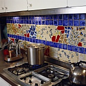 Mosaik-Rückwand hinter dem Gasherd und der Edelstahl-Arbeitsfläche in einer Küche