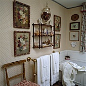 Blumen-Bilder auf beiden Seiten des viktorianischen Wandregals in einem Badezimmer mit Handtüchern auf Messing- Handtuchhalter