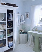 Hellblaues Badezimmer mit Wäschekorb und mit weiss gestrichenem Schrank