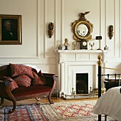 Biedermeier Sofa mit Mahagonirahmen und Kissen im weiss getäfelten Schlafzimmer mit vergoldetem Spiegel über Kamin
