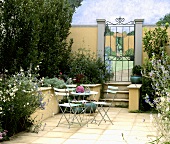 Gartentisch und Stühle auf der Terrasse in einem ummauerten Garten
