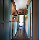 Treppenhaus und Flur mit blauen Zimmertüren und rustikalem Holzboden