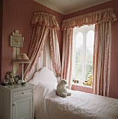 Kinderzimmer im traditionellen Landhausstil mit rosa weiss gestreiften Tapeten an Wand und Baldachin über Bett