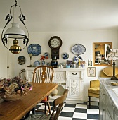 Hängelampe über Holztisch und Schachbrettmusterboden in alter Landhausküche