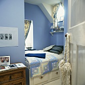 Hellblau getöntes Schlafzimmer mit eingebautem Bett und Schublade unter Dachschräge